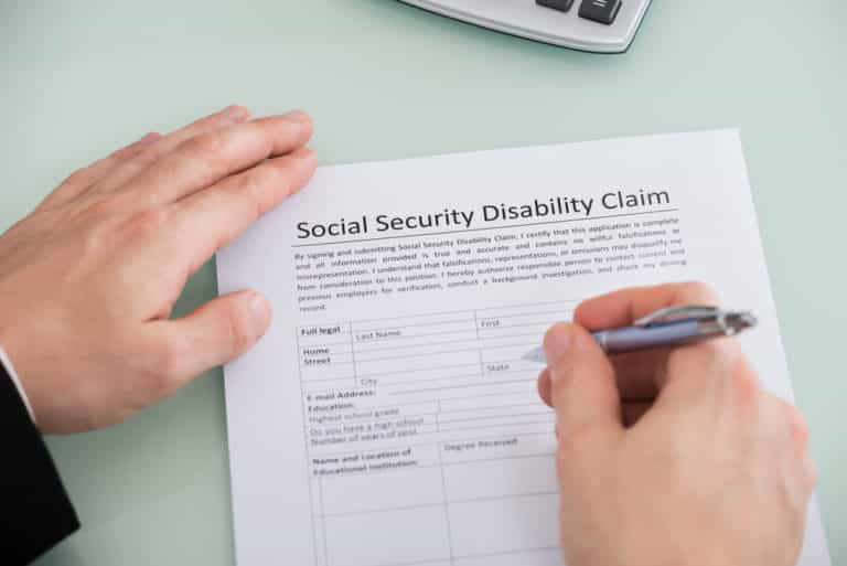 Close-up of hand completing social security disability claim