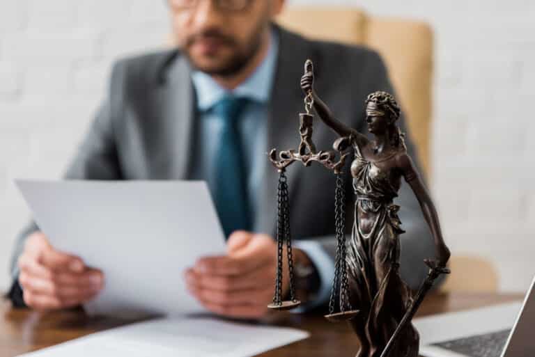 Lady of justice figurine, lawyer looking at paper in background