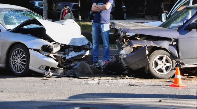 Man standing behind car collision aftermath