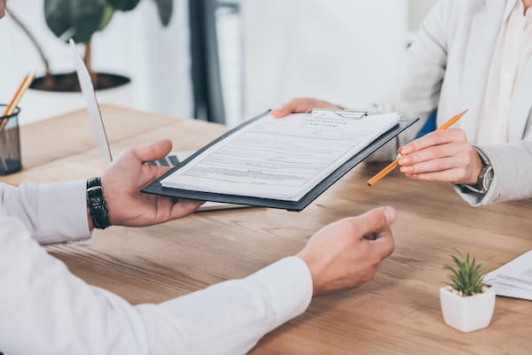 Close-up of employee handing another employee a workers' compensation claim form