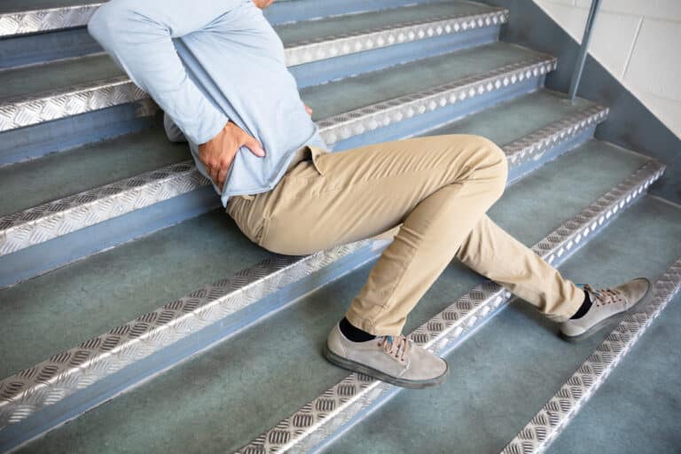Man fallen on steps, touching his back in pain