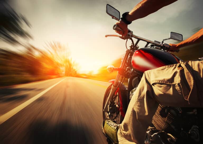 Close-up blurry photo of man on motorcycle at sunset