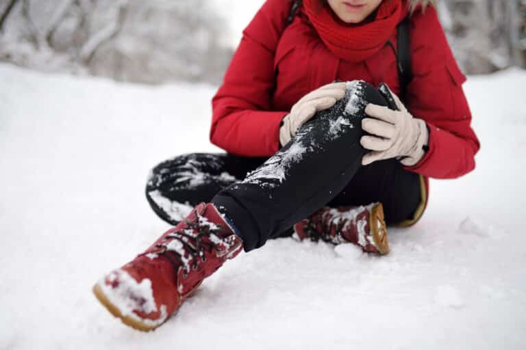 Woman on ground in the snow, holding knee