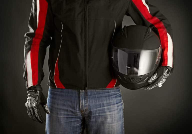 Close-up of torso of motorcyclist holding helmet