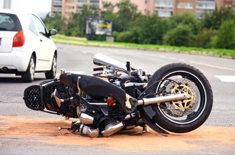 Motorcycle and vehicle collision, motorcycle lying on side on street