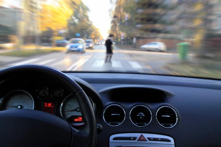 View out car dashboard, person crossing road in front of car