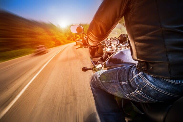 Close-up of motorcycle rider driving fast on road