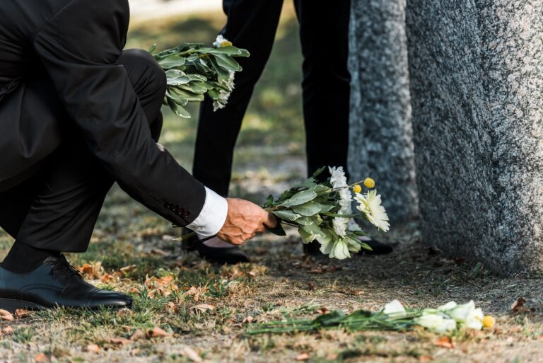 Man kneeling to place flowers beside a grave