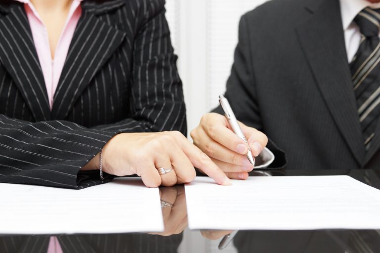 Woman pointing to legal document, man signing